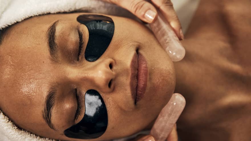 A woman getting a facial using crystals at a spa.