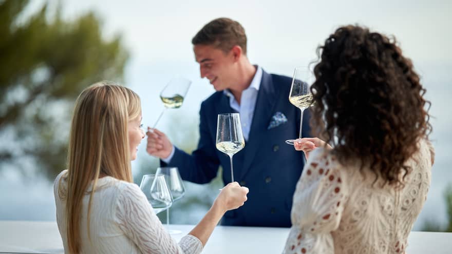 Head Sommelier Alessandro Nigro Imperiale sniffing glass of white wine with two female guests doing the same