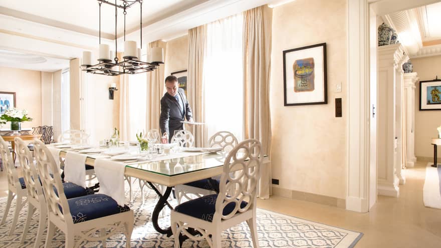 Hotel staff sets long table in bright Villa Rose-Pierre dining room