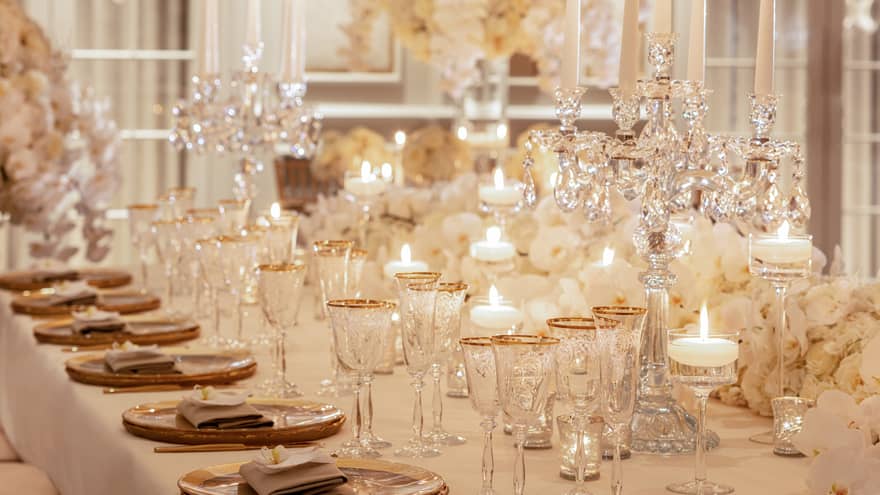 Wedding dining table filled with crystal wine glasses, glowing candles
