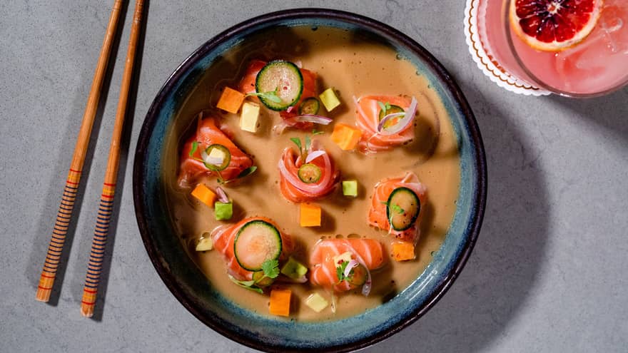 A bowl of raw salmon in an orange sauce.