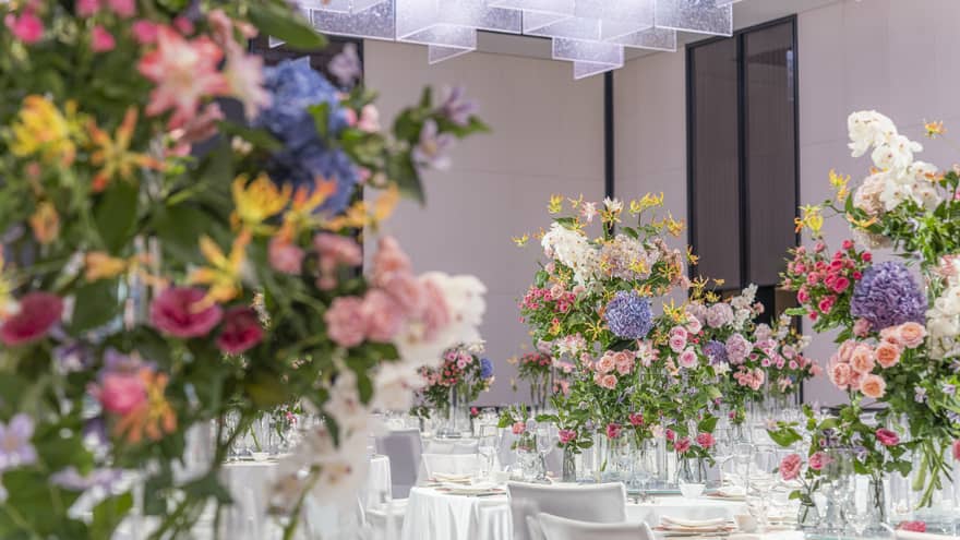 Hotel ballroom with banquet tables featuring large colourful floral arrangements