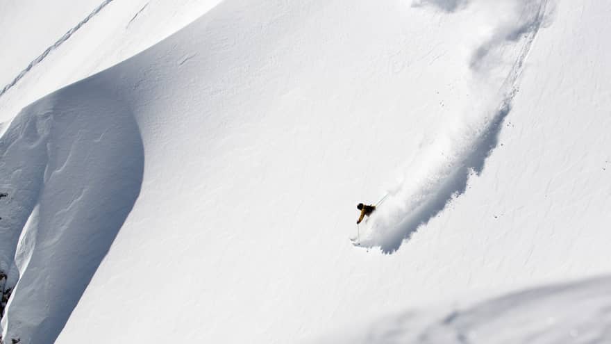 A person skiing down a slope of white snow.