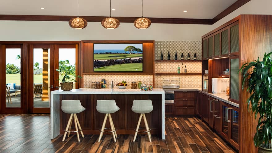 A kitchen area with an island, stools, cabinets, and large windowed door.