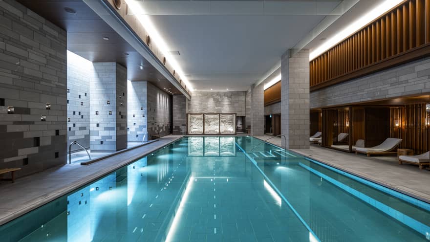 Indoor spa pool flanked by chaise longues and grey brick columns
