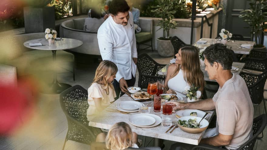Family of four dines at a table on a restaurant terrace