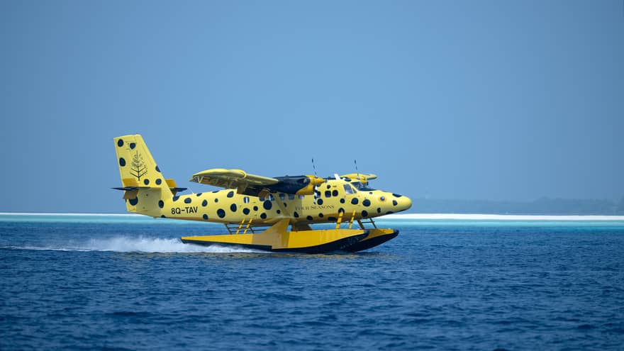 Yellow and black-spotted single-engine plane lands on the water in the Maldives