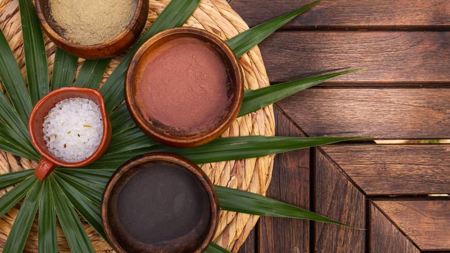 Various spa minerals in bowls on a large leaf.