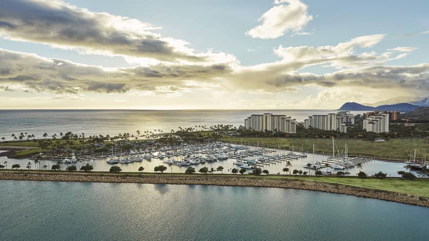 Aerial view of harbour lined with yachts, resort buildings at sunset