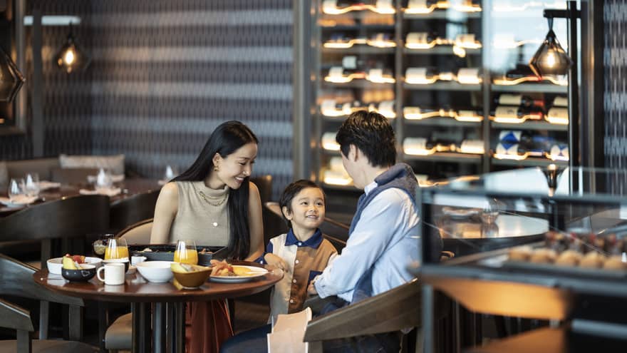 Parents and a child sitting at a dining table enjoying breakfast together