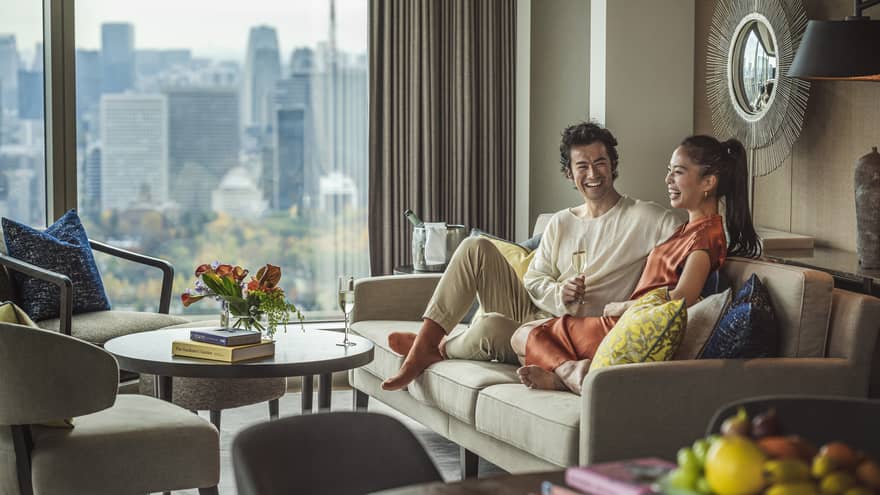 Two people sitting on a sofa, smiling and enjoying a drink together