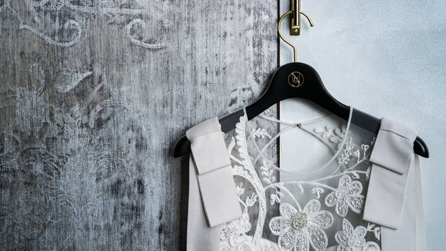 Close-up of wedding dress on hanger with lace flower bodice