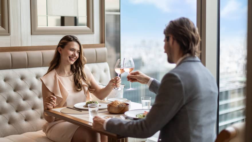 A couple toasts with wine at est, a refined French restaurant in Tokyo, enjoying fine dining with a view.