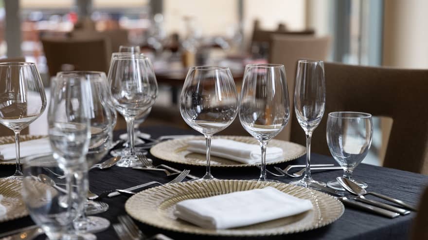 A dining table set with wine glasses, plates and napkins