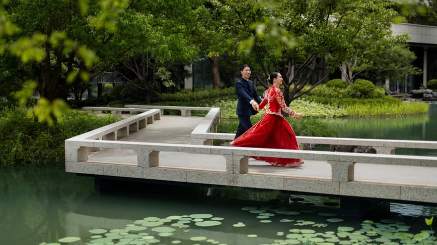 Man and woman walk along pond garden pathway in Suzhou