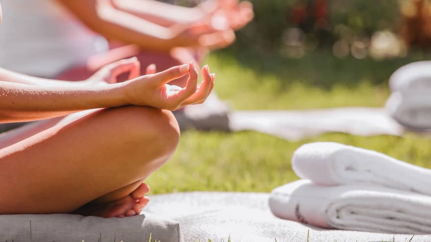 A group doing yoga outside with mats and towels.