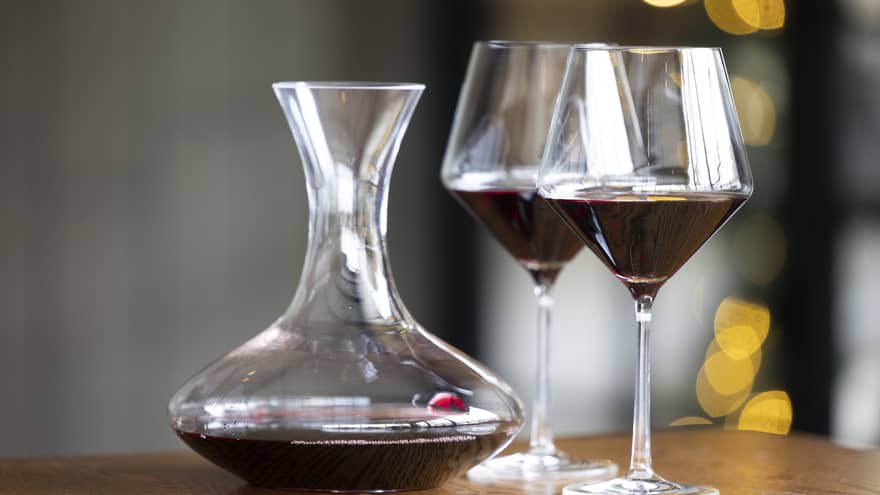 Two wine glasses on a table beside a wine pitcher