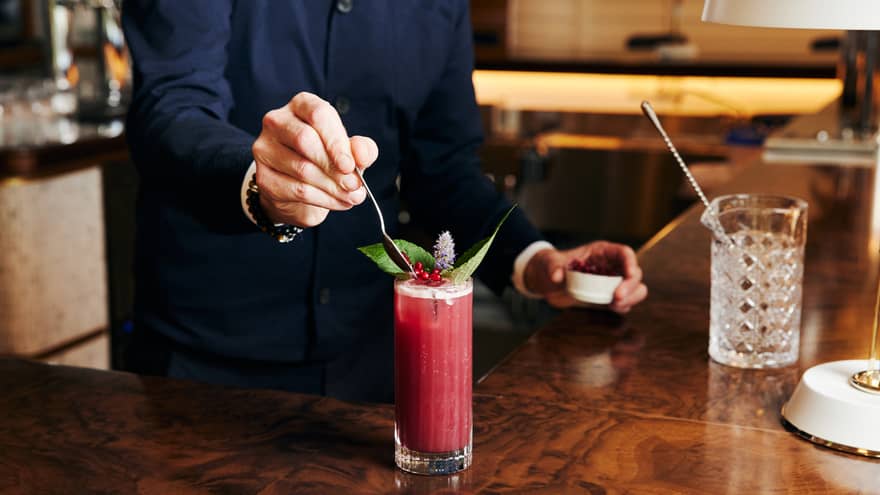 A bartender making a bright pink cocktail.