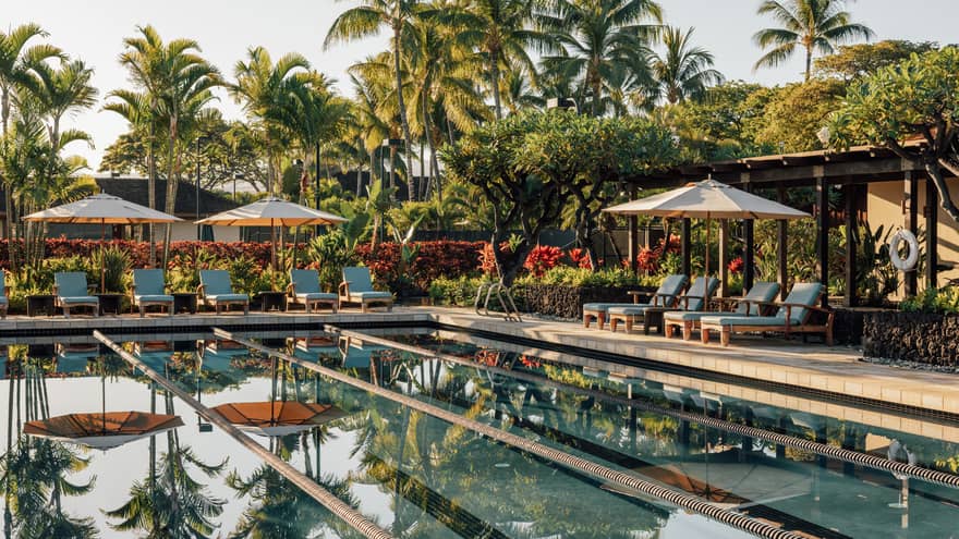 Outdoor lap pool with tropical palm trees and lounge chairs at Four Seasons Resort Hualalai, Hawaii
