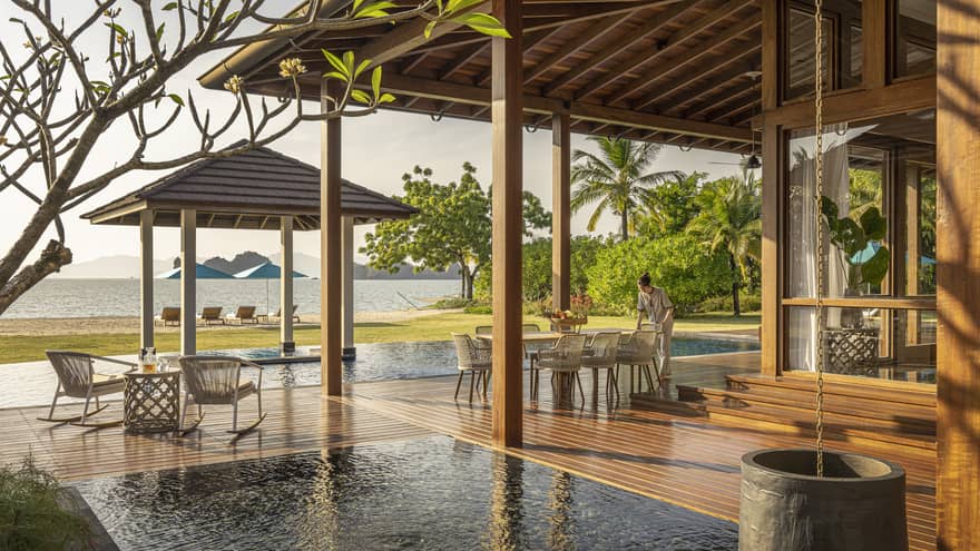 Private pool terrace and wooden deck under pergola, looking out to green lawn and Langkawi beach