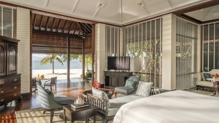 Bedroom with chaise and two arm chairs, plus opening to covered terrace and beach