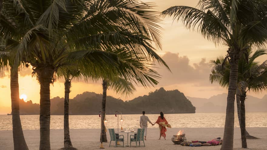 A man and woman on a beach having a Punta chintai private dinner at Four Seasons Langkawi