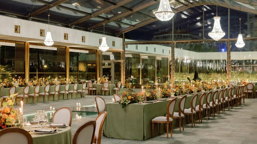 Rows of lavish wedding tables under crystal chandeliers at night
