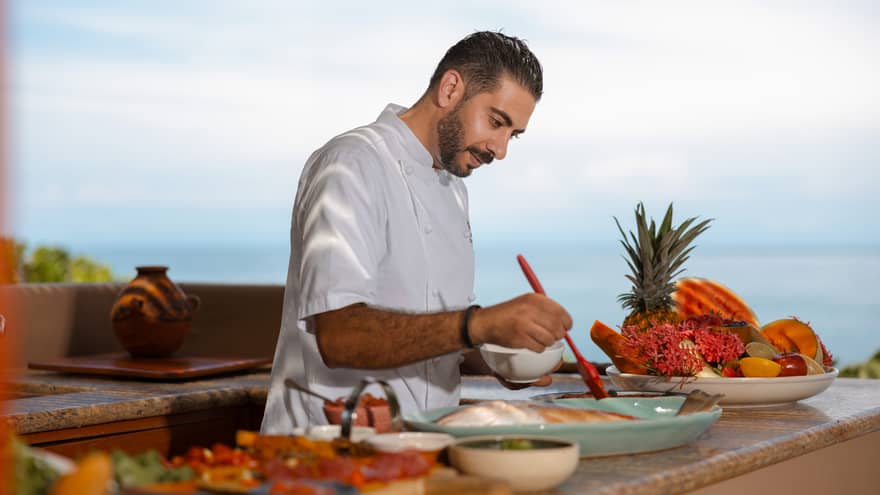 A chef prepares food in an outdoor cooking area.