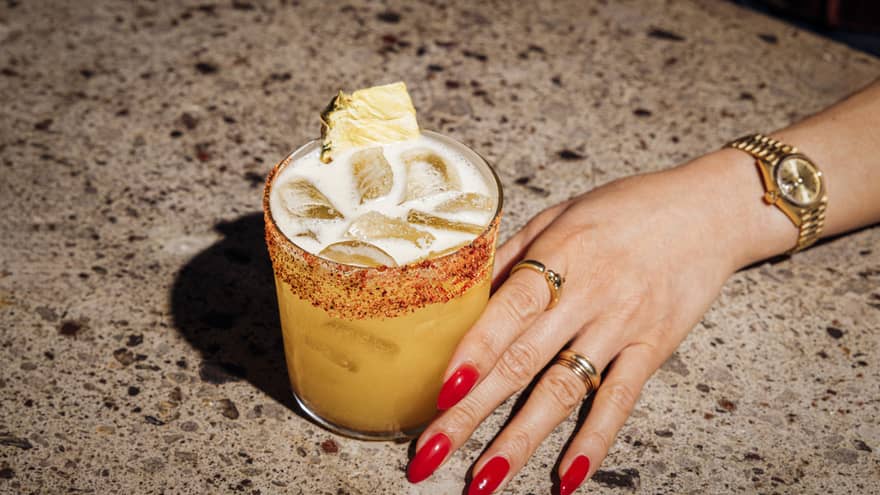 Pisco cocktail and woman's hand with red nail polish