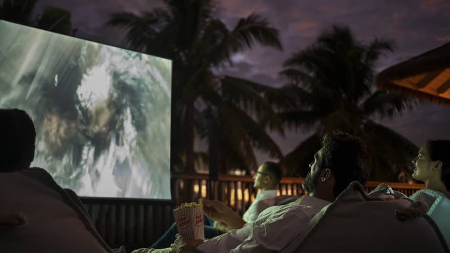 Group of people sit on bean bags with popcorn watching movie under the stars 