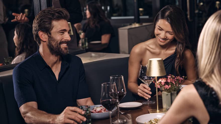 Three guests sitting at a dining table while talking and laughing.
