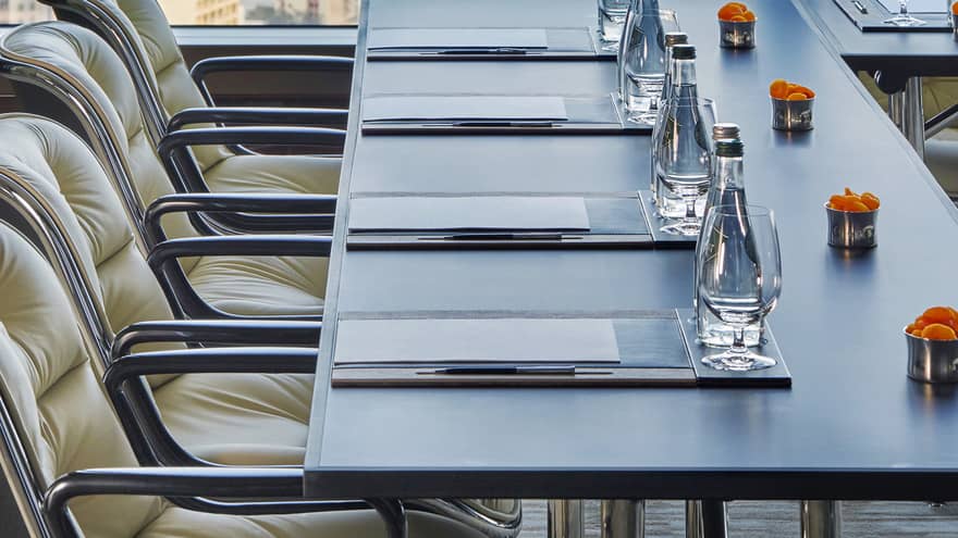 Close-up of meeting table with water, orange flowers by sunny window
