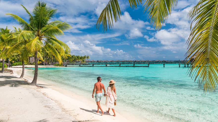 Couple walking on the white-sand beach in Bora Bora