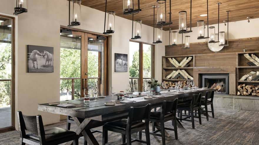 Dining room with hanging lights, a fireplace, a rectangular table and chairs.