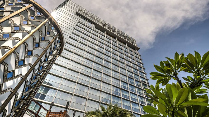 View looking up past tropical plant to glass Four Seasons Hotel Jakarta tower 