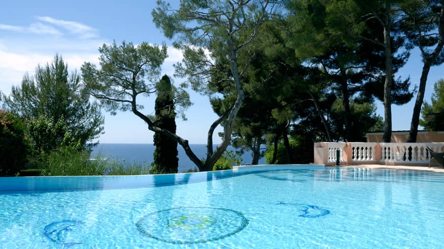 Blue outdoor swimming pool, trees, sea views