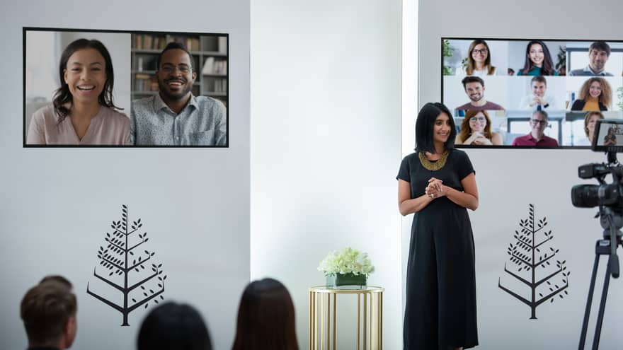 Several people host a virtual meeting in a room with the Four Seasons logo.