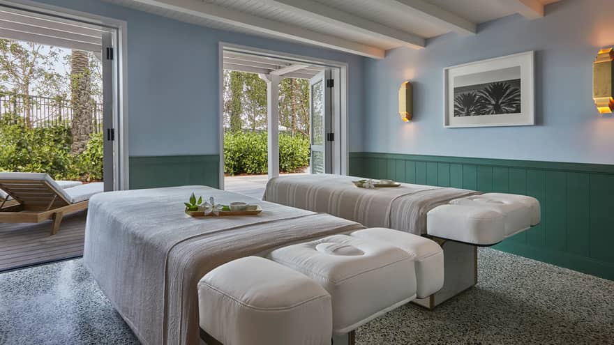 Couples massage beds side-by-side in spa treatment room, open patio doors 