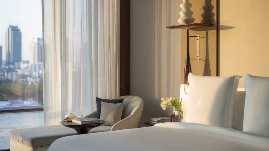 Hotel room with king bed, chaise and window with river and city view