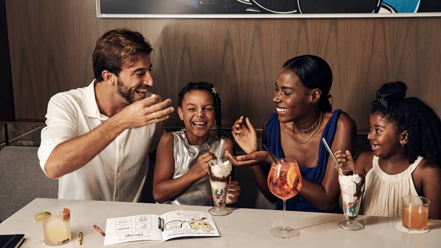 Family sitting at the table laughing and eating ice cream sundaes.