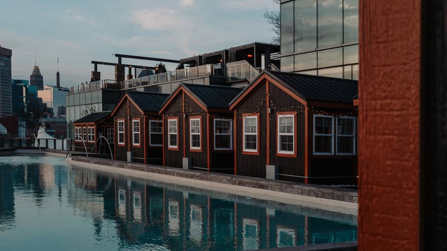 Four cottages with orange trimming beside a pool and city buildings