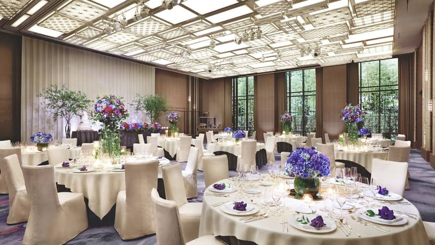 Ballroom event with round banquet tables under patterned, panel ceiling, lights