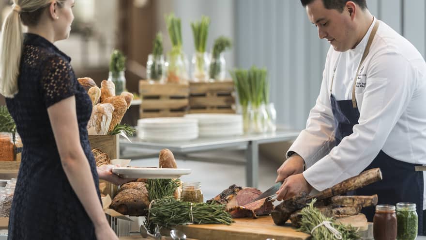 A chef cutting steak for a guest at the Sky Bridge