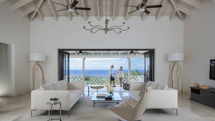 Living room with modern white furniture in front of open doors to sunny patio, couple