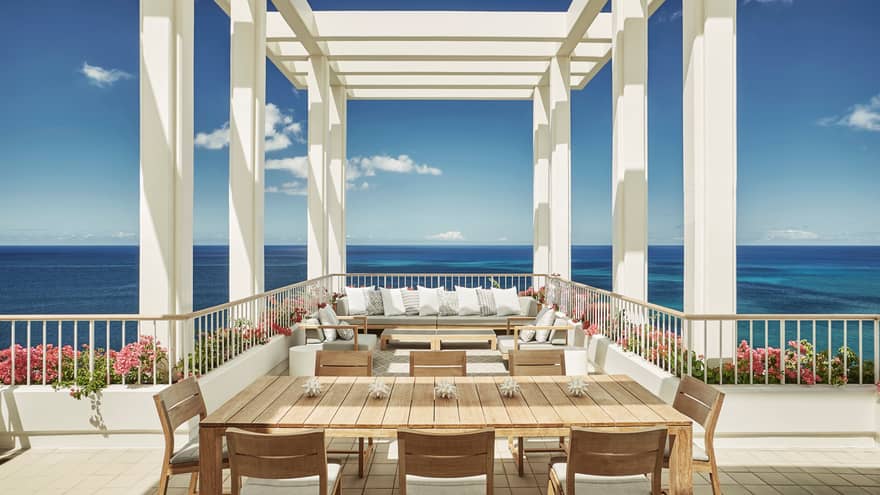 Penthouse Suite large patio dining table, seating area under white pergola, blue sky