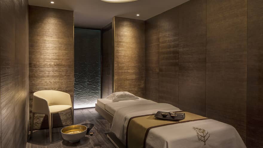 View of private massage room in spa and wellness centre, wood grain walls and low lighting