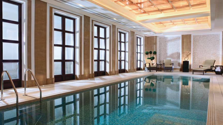Floor-to-ceiling windows reflecting on long indoor swimming pool