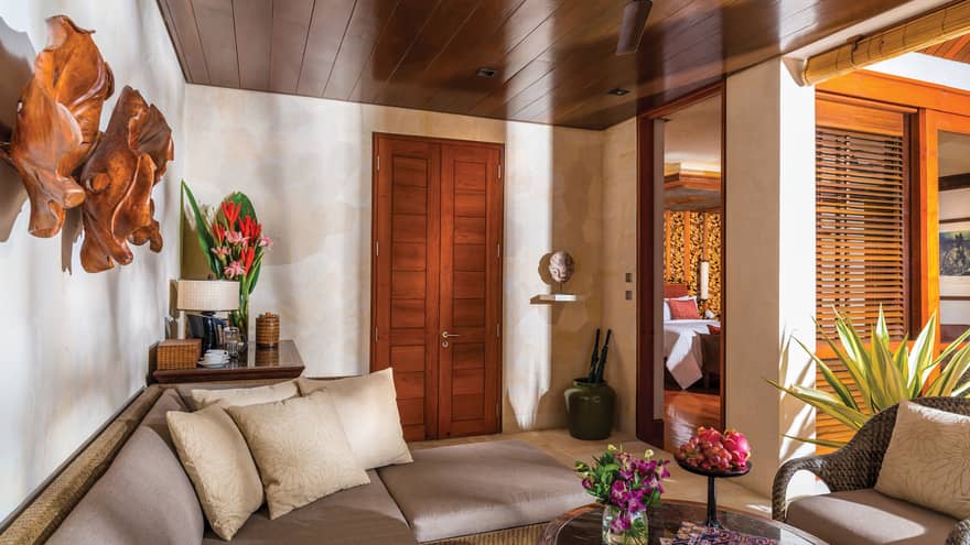 One Bedroom Villa Living area with cream sectional and armchair, oval coffee table, exotic wall art