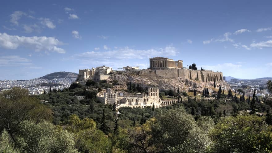 Ancient ruins of Acropolis on mountain surrounded by greenery 
