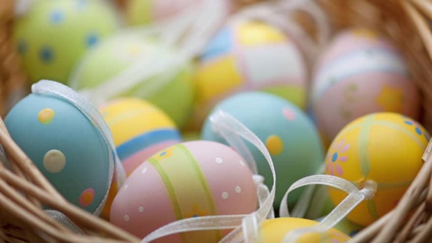 A basket of blue, pink, green and yellow colourful Easter eggs.